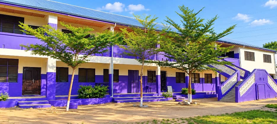 Two-storey purple and cream classroom block with young trees in the courtyard