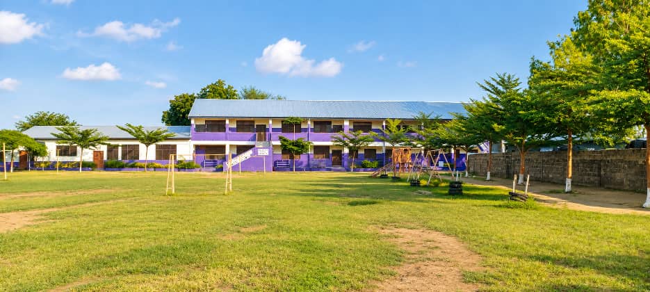 School playground with swings and open field in front of the main building